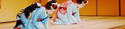 Geishas in traditionellen Kimonos knien auf einer Tatami-Matte