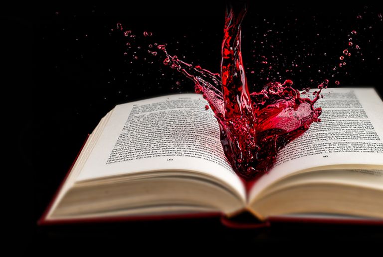 Offenes Buch mit spritzendem rotem Wein auf schwarzem Hintergrund - DART