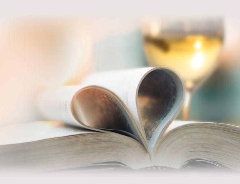 Aufgeschlagenes Buch mit zwei zu einem Herz geformten Seiten und einem Glas Weißwein im Hintergrund - DART